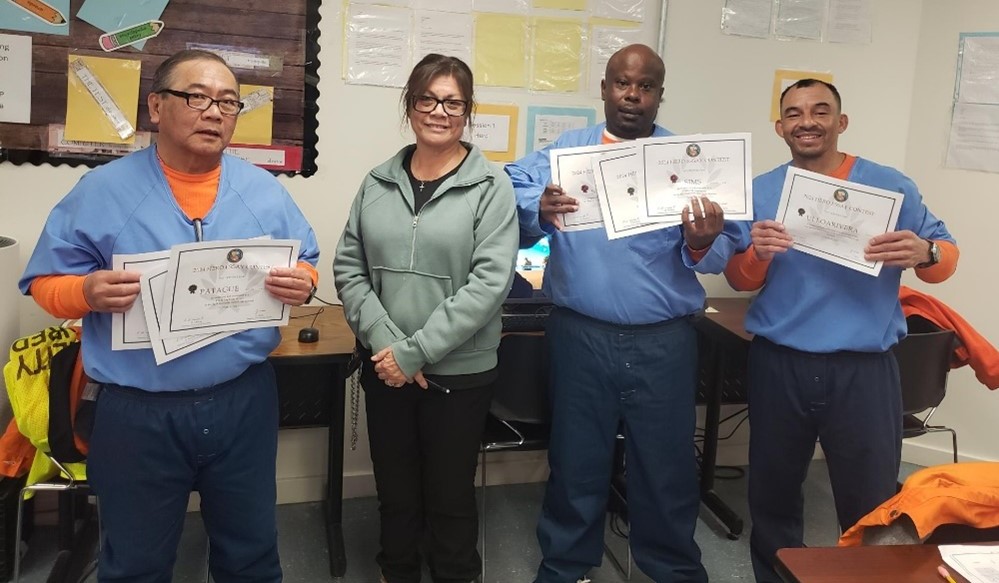 Three essay contest winners at High Desert State Prison with an educator.