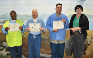 Three Pelican Bay State Prison essay writing contest participants with an educator.
