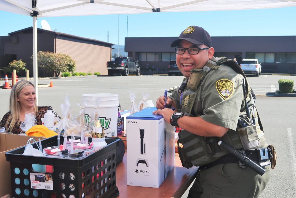 Pelican Bay State Prison Employee Appreciation Day with an officer smiling while filling out an entry form for a prize drawing.