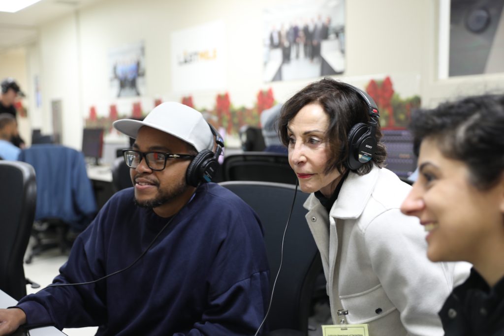 A woman wears headphones to listen to an audio/video project at San Quentin.