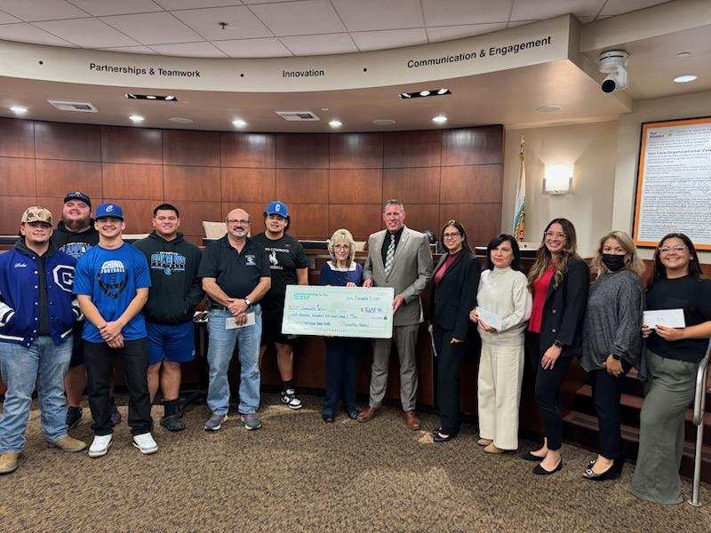 CDCR officials are shown presenting a check during a city council meeting.