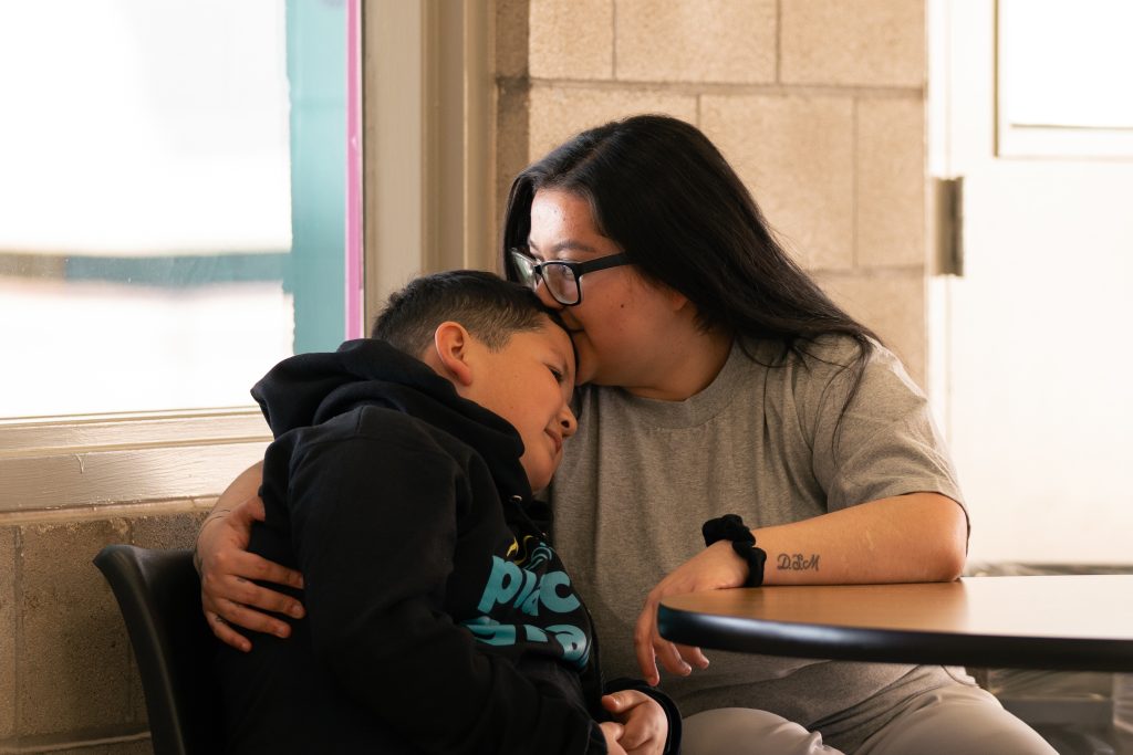 A mother hugs her child in a prison visiting room. 