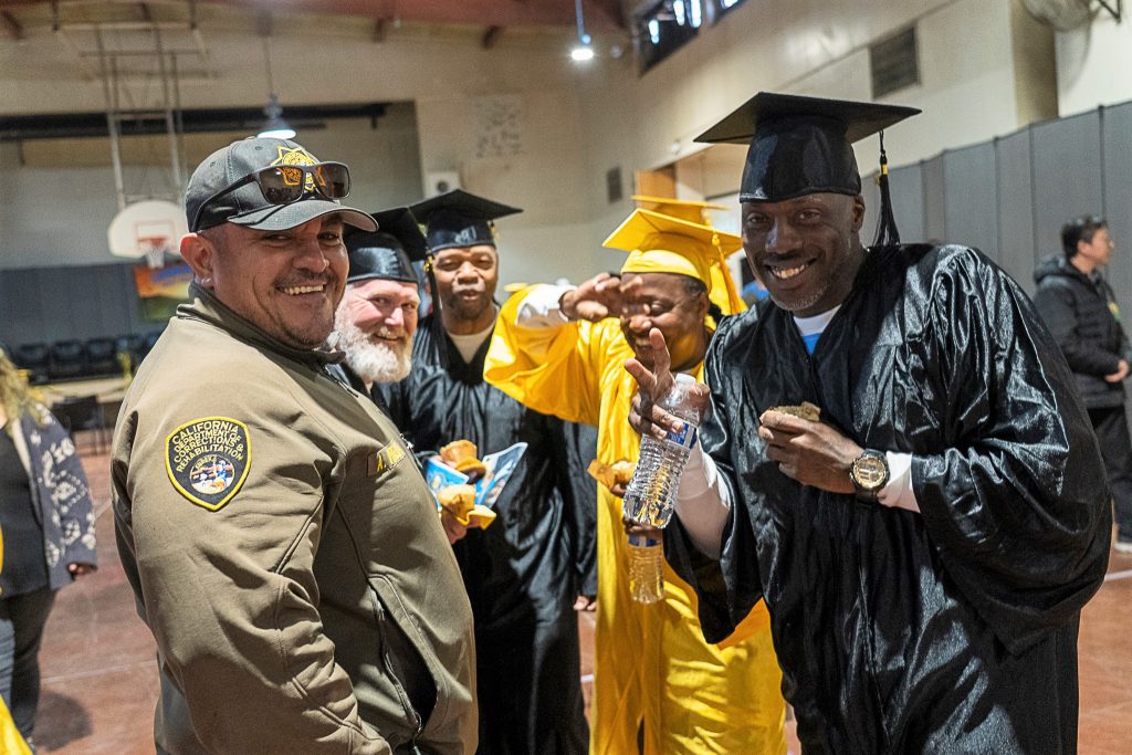A correctional officer with four incarcerated students after their education graduation.