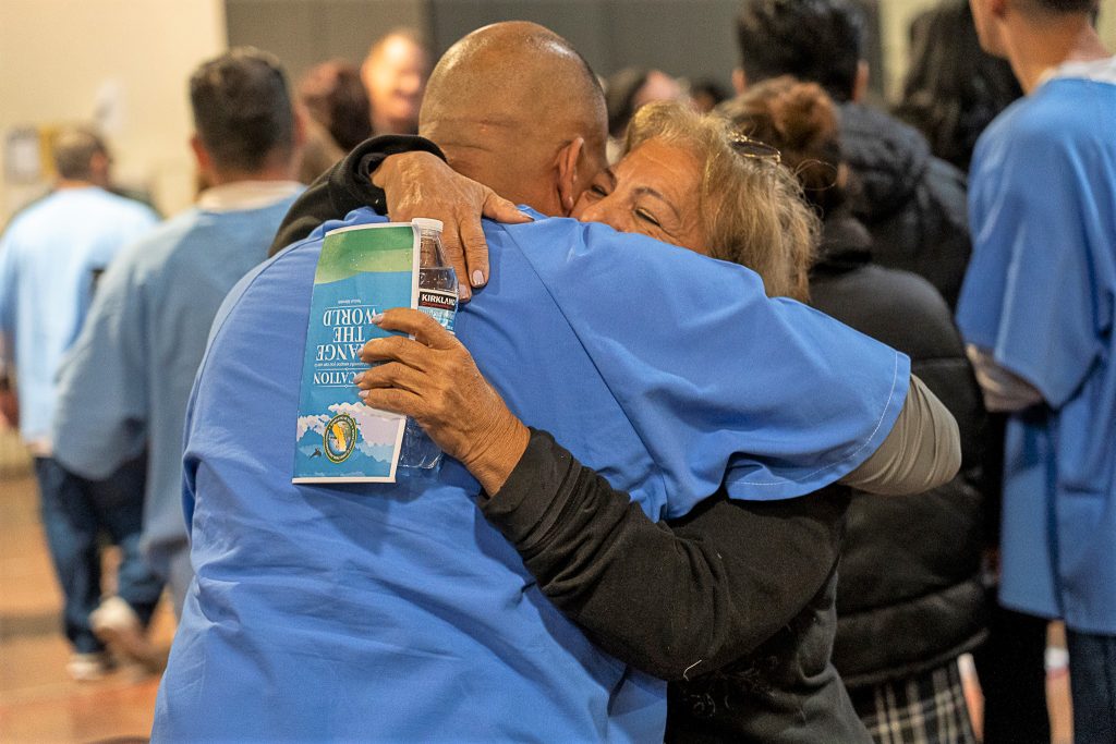An incarcerated person hugs a loved one after the graduation ceremony.
