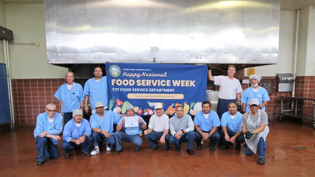 Food Service Week at CTF group photo of incarcerated people and staff in the institution's kitchen.