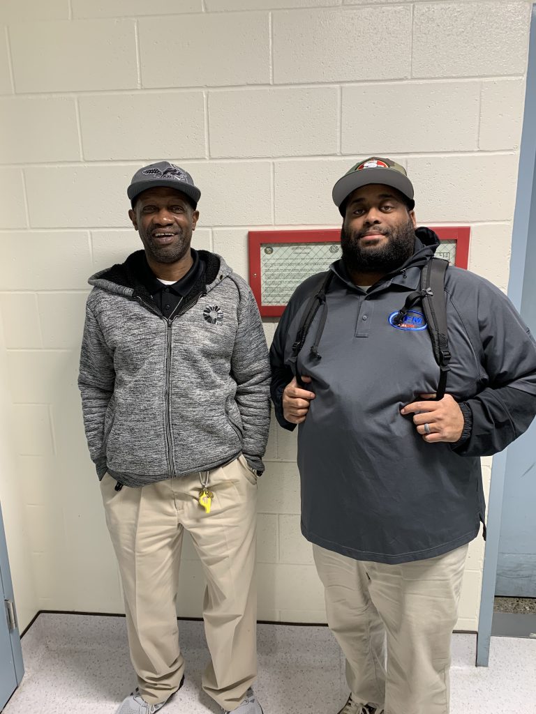 Two staff members wearing sports hats.