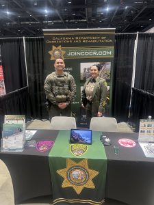 Two correctional officers standing at recruitment booth at Women's Conference