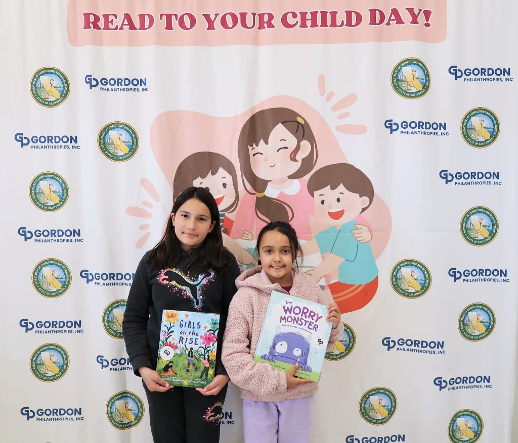 Two kids hold books at a Read to Your Child Day event at CIW. 