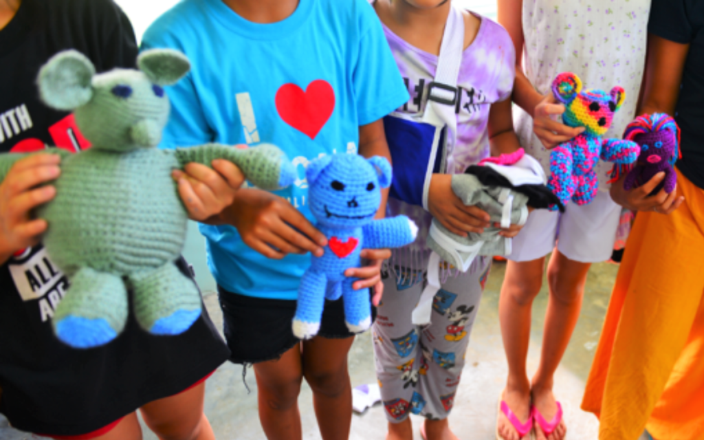 Donation of stuffed animals from an SCC crochet group are held by kids in the Philippines.