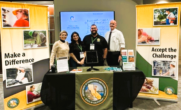 Four CDCR recruiters standing at their booth at Tulare County hiring fair 