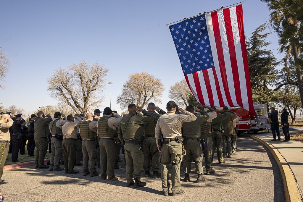 Staff salute the flag at the memorial for Manny Gonzalez.