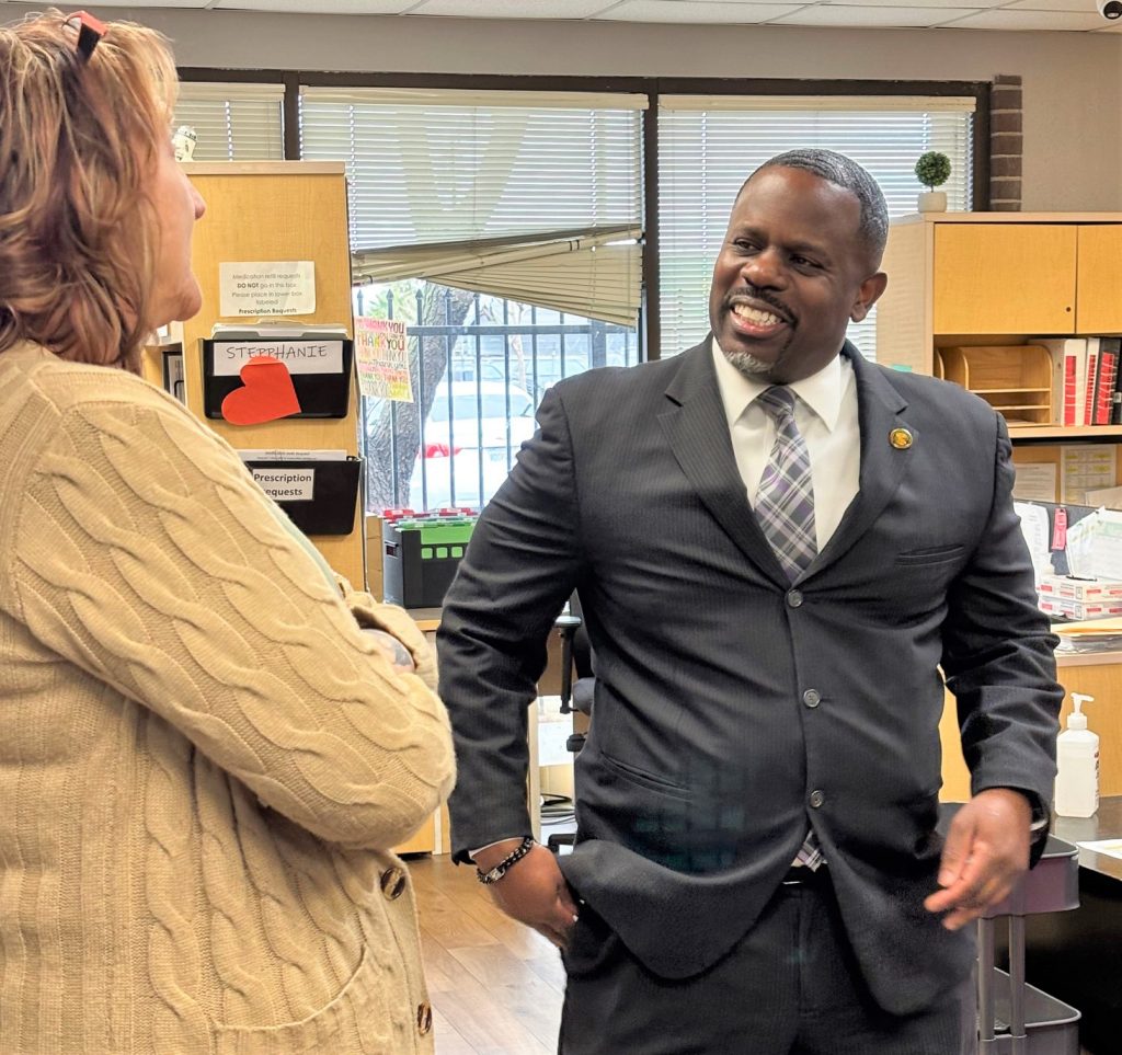 Two people smiling while standing in an office.