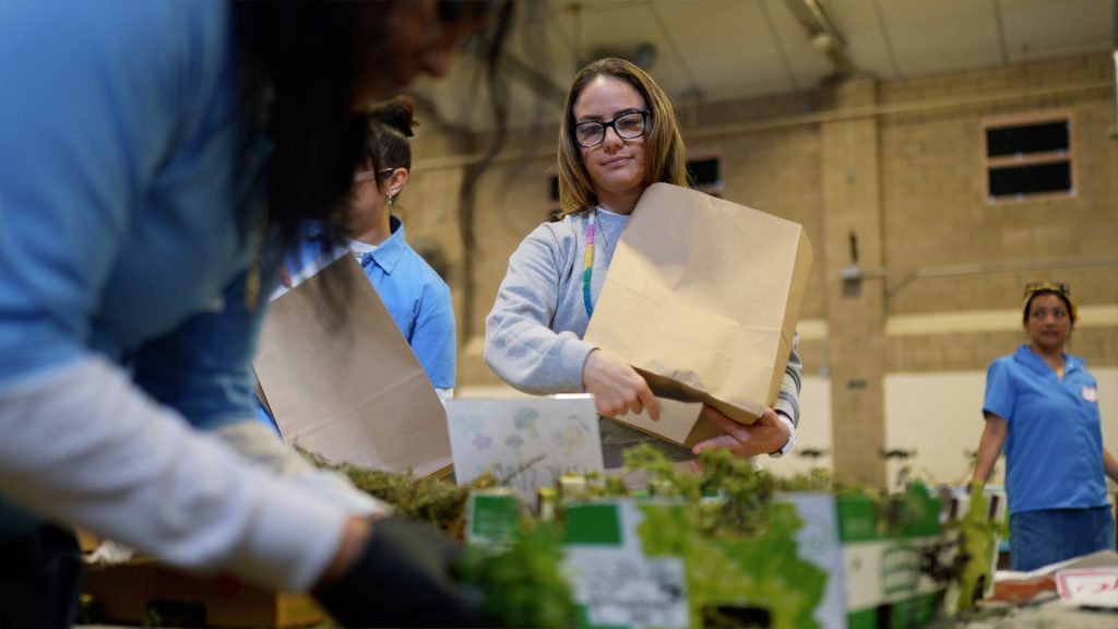 A woman holds a bag of fresh produce.