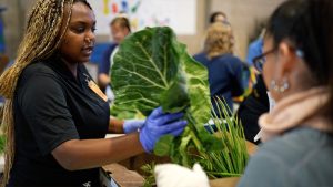 A woman offers fresh produce to another person at a farmers market at CCWF.
