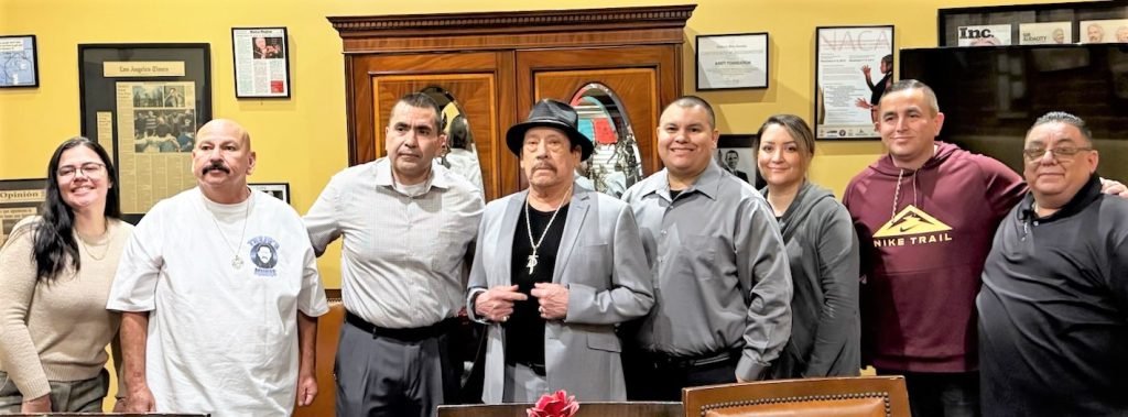A group photo of Danny Trejo with people at a Male Community Reentry Program in Los Angeles.