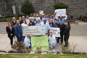 Group of incarcerated individuals and staff holding Girl Scout cookie sale fundraising check