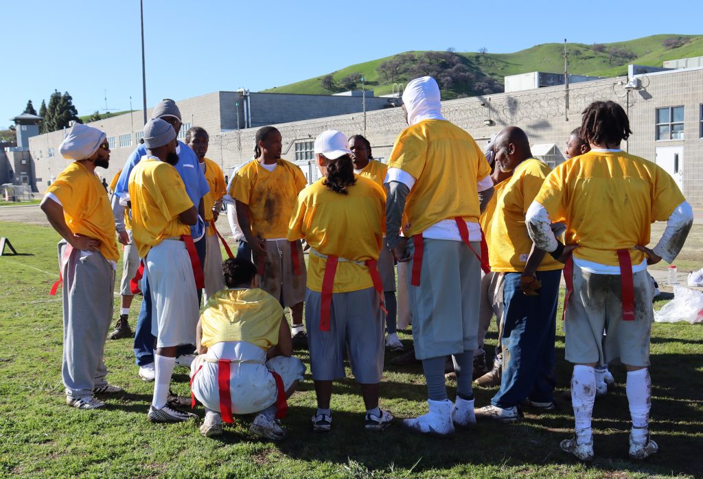 Flag football players in a huddle at California State Prison, Solano.