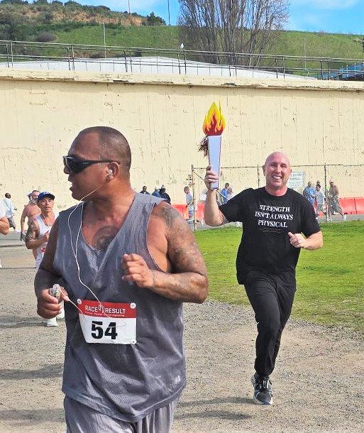 Warden Chance Andes carries a mock torch during the run at San Quentin.