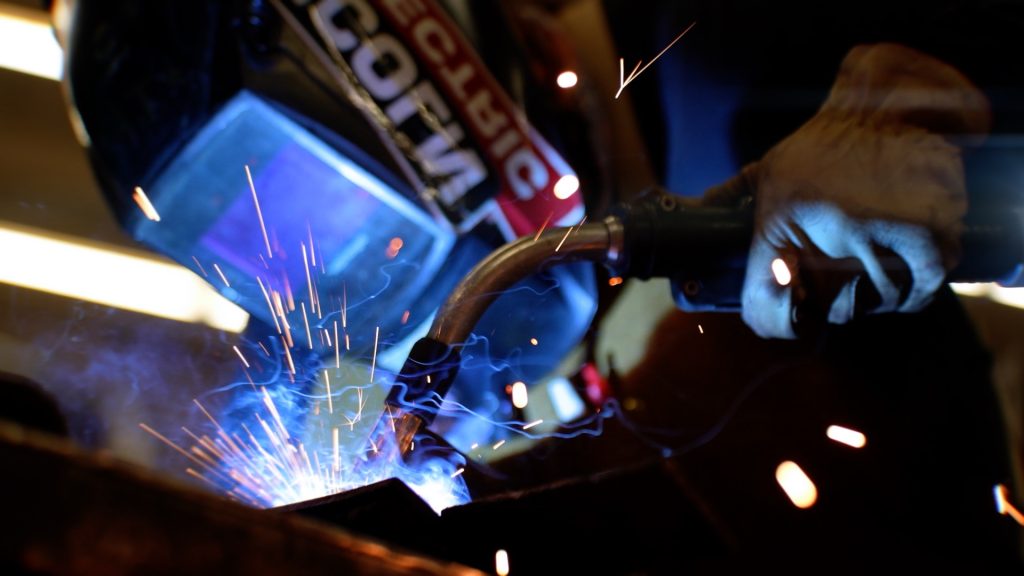 Tiffany Orff, welding instructor, wearing a helmet while sparks fly around her.