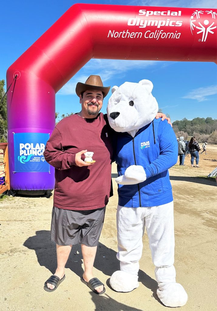 A man wearing a cowboy hat with a polar bear mascot for the Special Olympics Polar Plunge. 