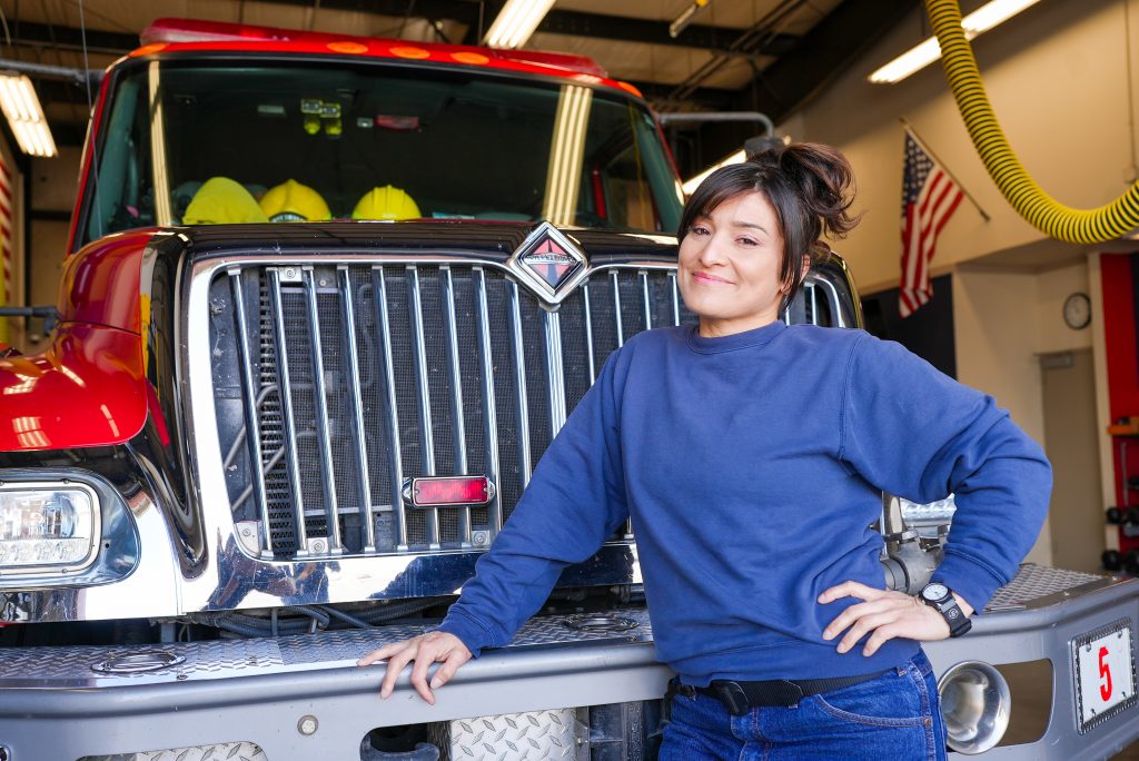 CCWF firefighter female incarcerated in front of a fire engine.