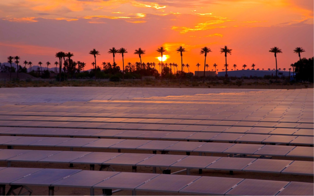 CDCR honors Earth Day with major sustainability milestones such as solar and wind power, zero-emission vehicles, water conservation, and green building practices. The photo shows a sunset with solar panels and palm trees in the background at a prison.
