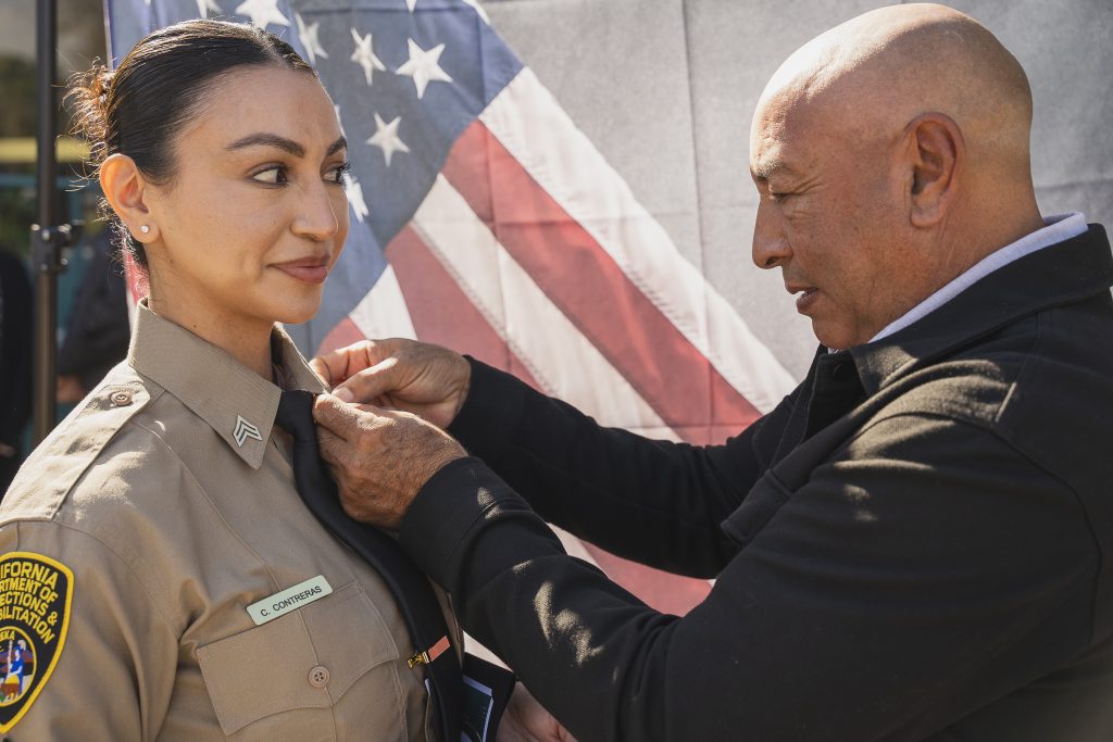 Man pins rank on a woman's uniform at CIM.