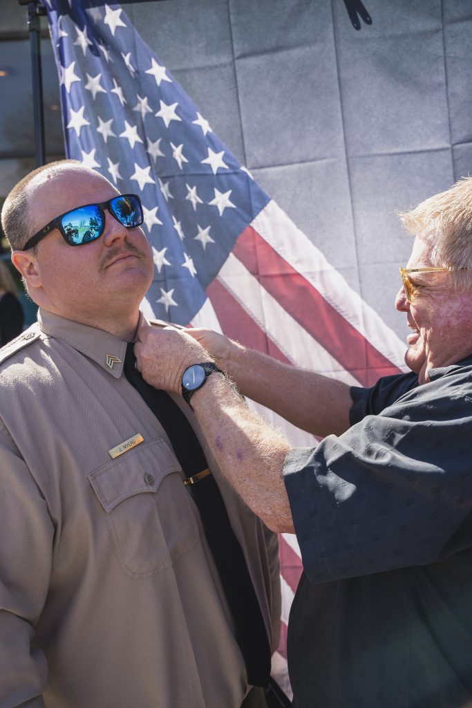 A person pins a new sergeant's rank on another person. 