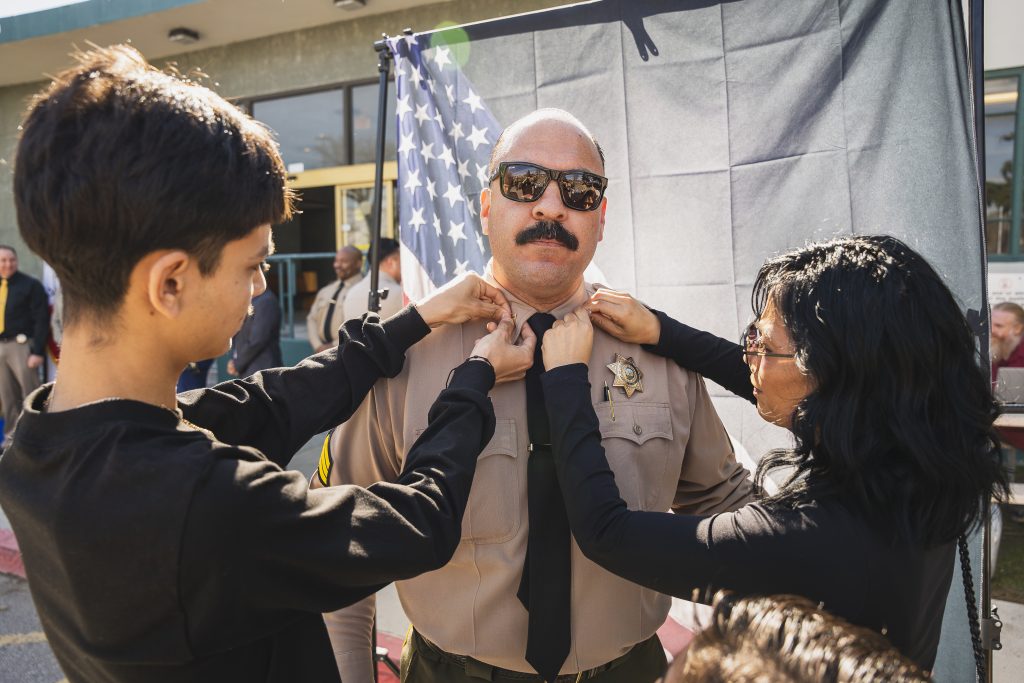 Family pins sergeant's rank on a man's uniform.