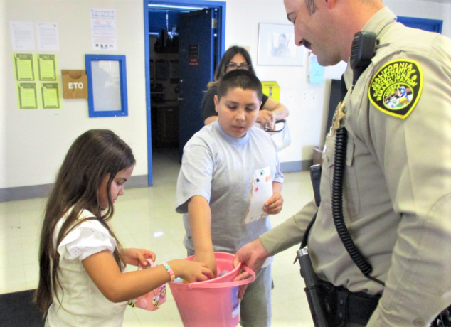 An officer lets children choose treats from a basket at CSP-Corcoran.