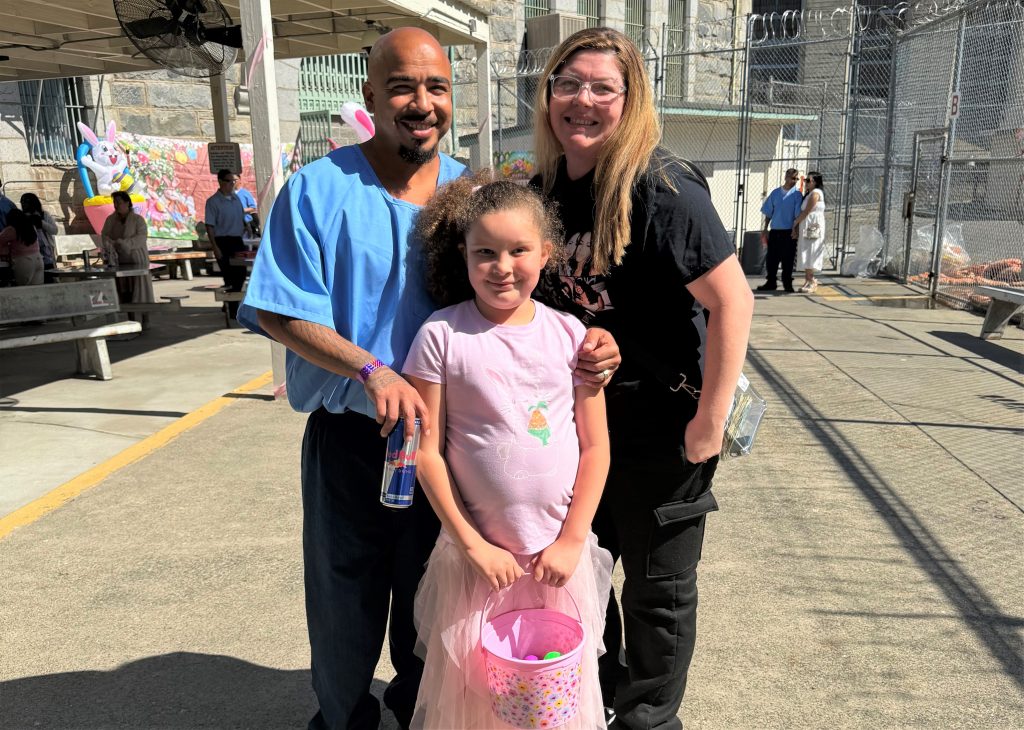 A child with a woman and an incarcerated man at Folsom State Prison for Easter visiting. 