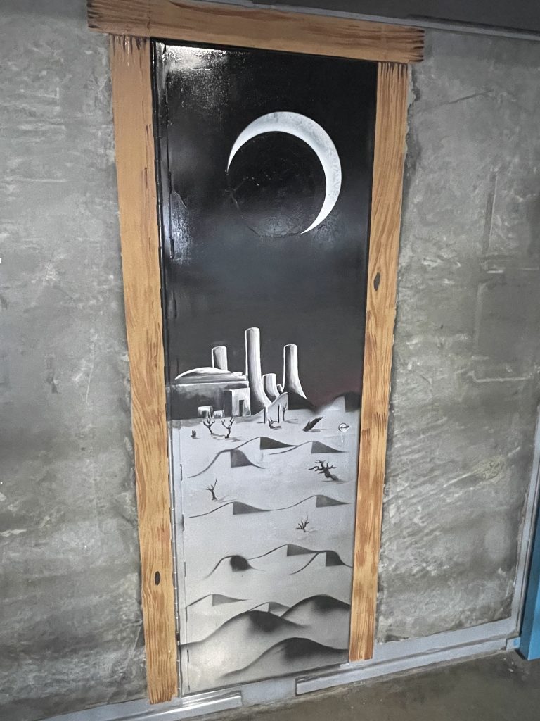 Art project black-and-white painting of a desert landscape with the moon in the background.