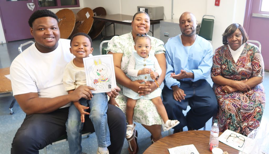 A family with two young children hold Easter drawings up for the camera at High Desert State Prison in Susanville.