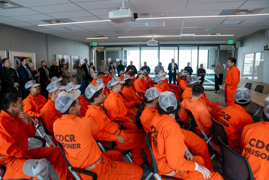 Pine Grove Youth Conservation Camp at the state capitol sit in chairs while listening to another crew member speak.
