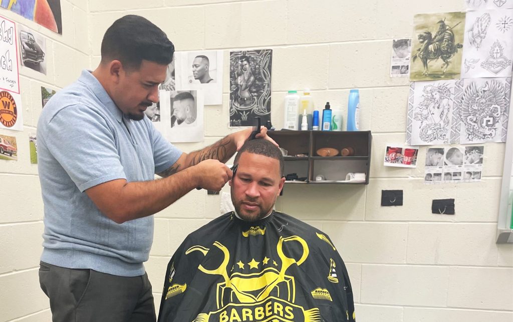 A barber demonstrates a haircut technique at a California prison.