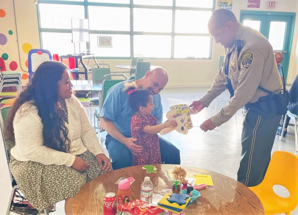 Staff member hands some goodies to a child at SATF.