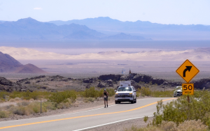 A runner with a follow car on the Baker to Vegas relay race in 2025 with mountains and desert in the background.