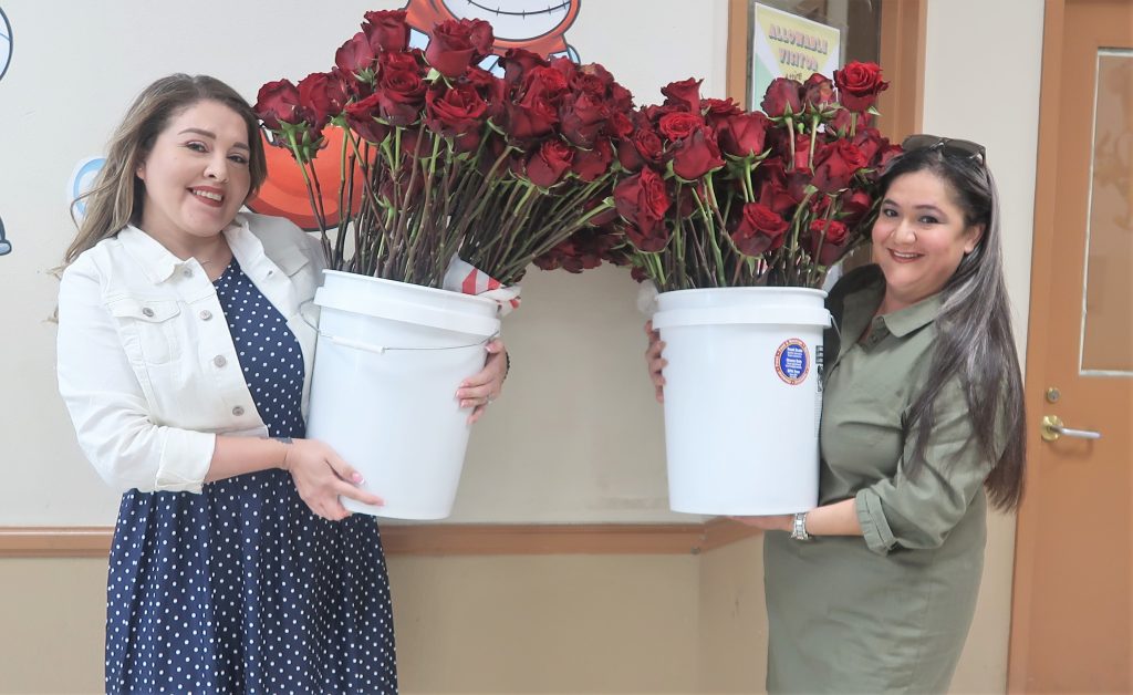 Two women hold buckets of long-stemmed roses to hand out during Mother's Day visiting at Calipatria State Prison.