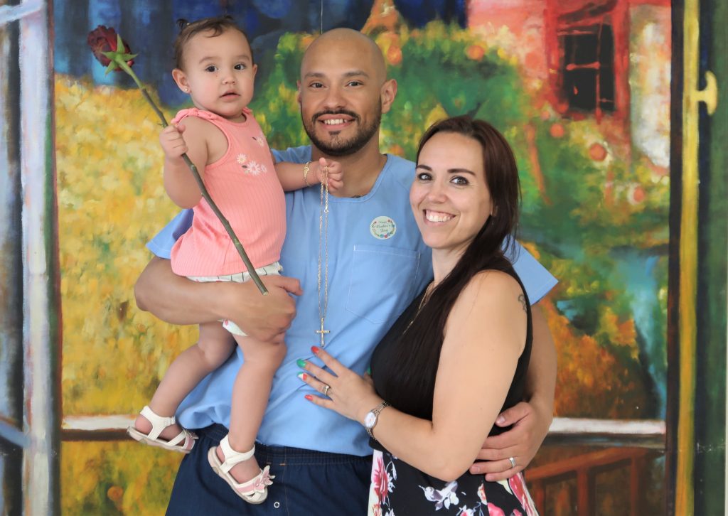 An incarcerated person holds a young child with a woman hugs him during Mother's Day visiting at Calipatria State Prison.