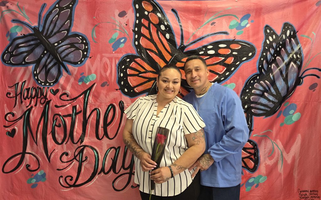 A woman holds a rose while posing for a photo with an incarcerated person at CCI-Tehachapi on Mother's Day, Sunday, May 11, 2025.