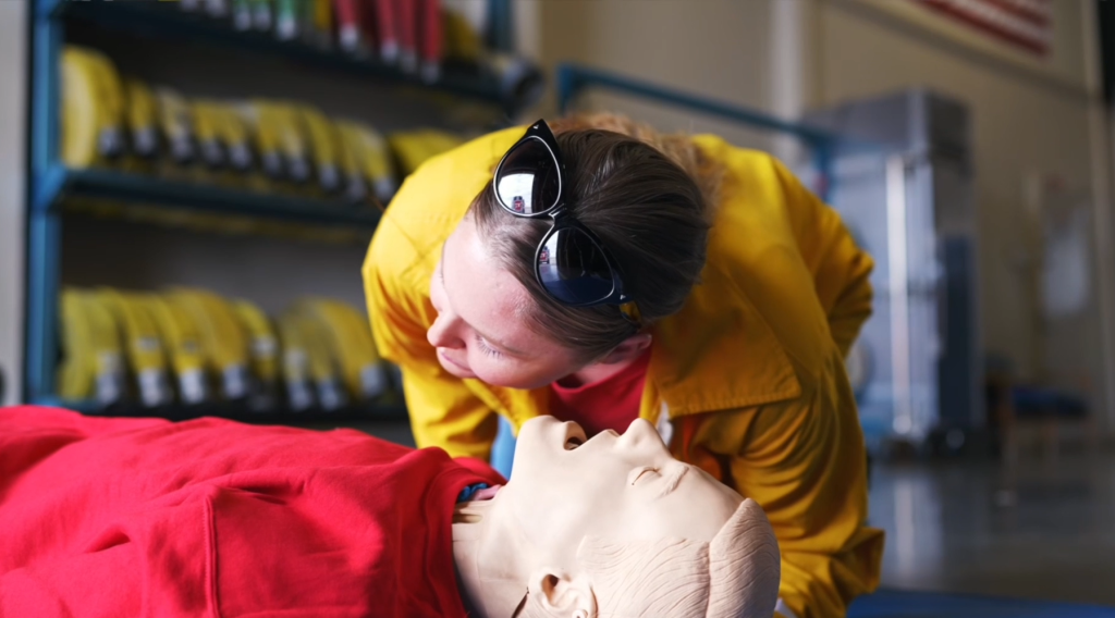 CCWF fire crew member demonstrates how to listen for breathing sounds while also looking out for chest rise and fall.