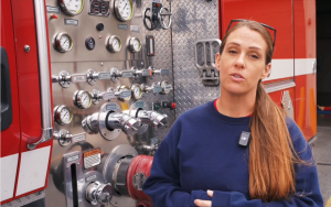 A CCWF fire crew member with a fire engine in the background for National EMS Week.