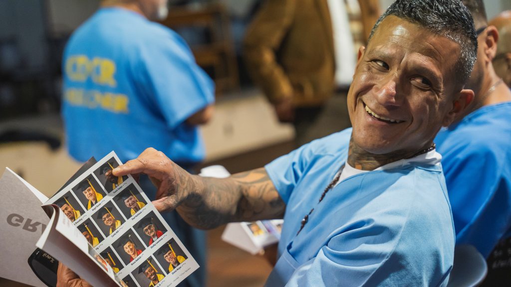 Incarcerated college graduate checks out the ceremony program at CIM.