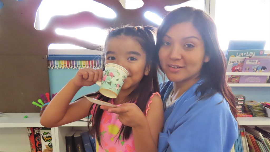 A child sips tea while sitting on her incarcerated mother's lap at California Institution for Women during Mother's Day visiting in May 2025 at Corona, California.