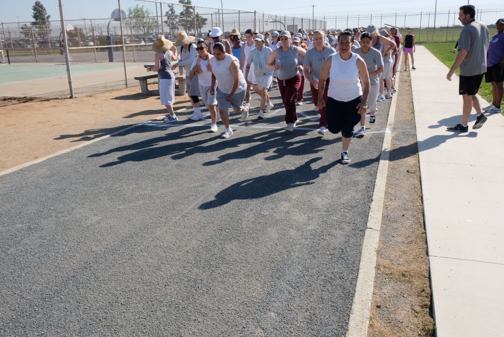 People walking and running on a track at California Institution for Women (CIW) as part of a 5k fundraiser for fire victims. 