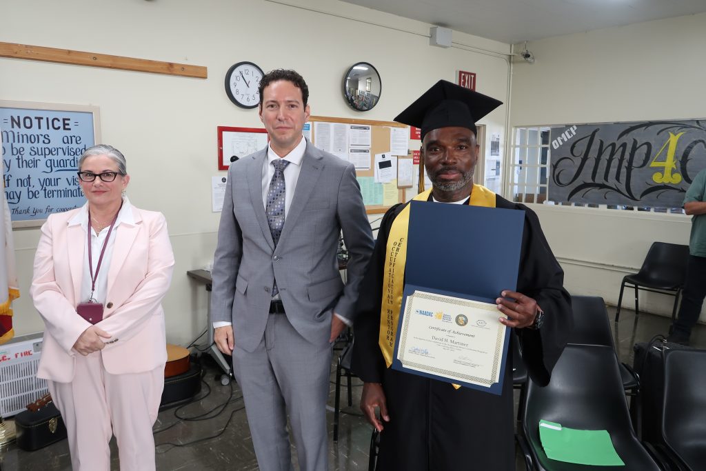 A proud graduate holds his certification at CMC.