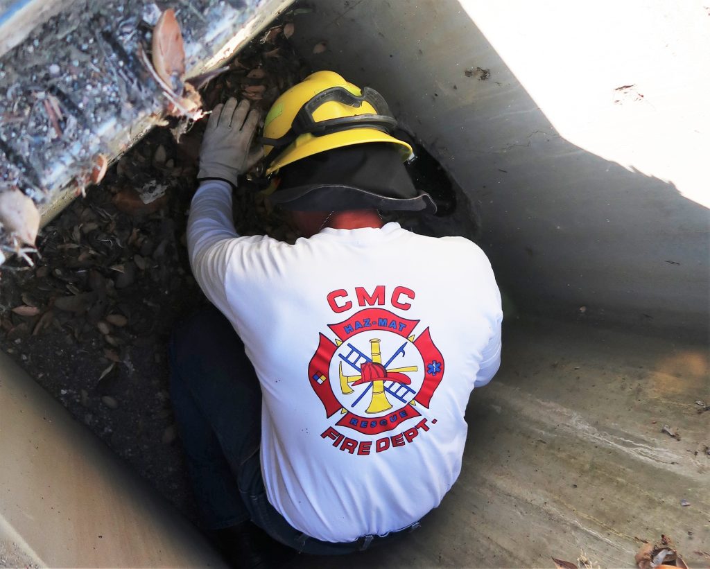 A firefighter climbs into a storm drain at CMC.