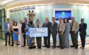 CSP-Corcoran executive staff present a check from cancer walks to Valley Children's Hospital in Madera. The hospital's mascot, a giraffe, holds the check.