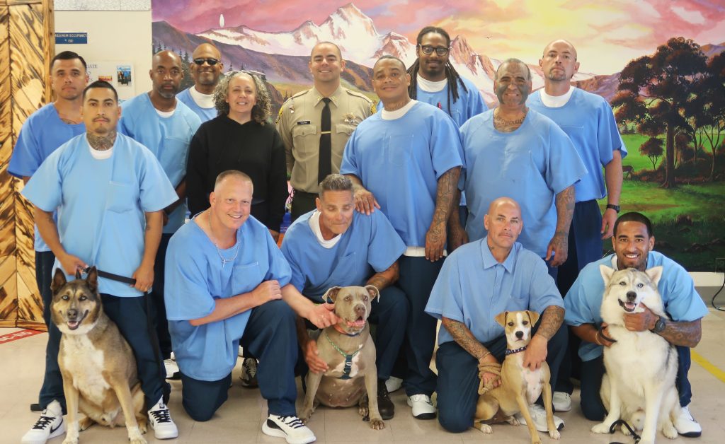 Group photo of the four dogs and their incarcerated trainers at CSP-Corcoran Facility 3B.