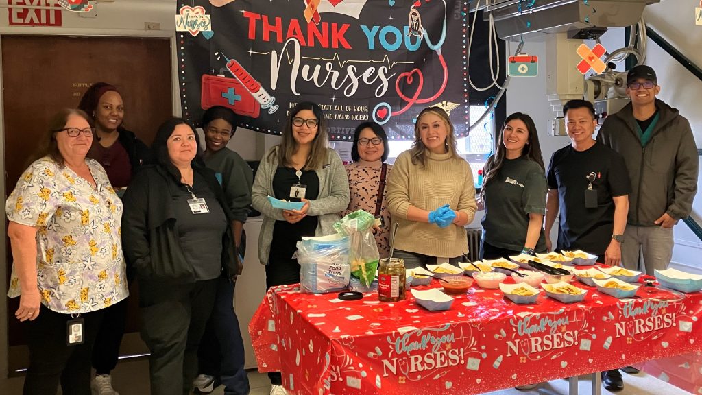 Thank you nurses banner hangs in background with a table full of nachos in the foreground and CRC-Norco staff standing behind it.